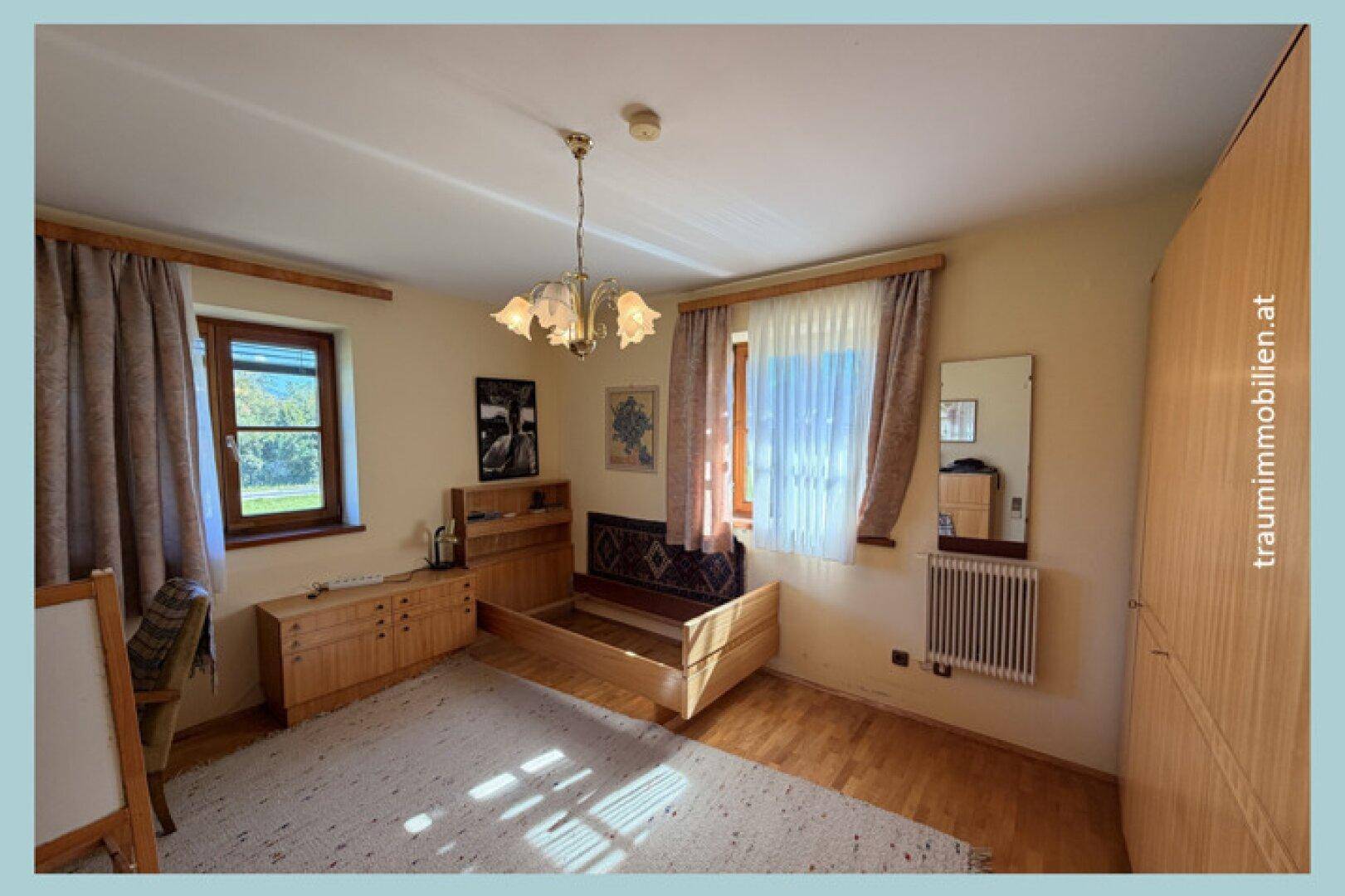Schlafzimmer mit Holzbett, Kommode und hellem Holzboden.