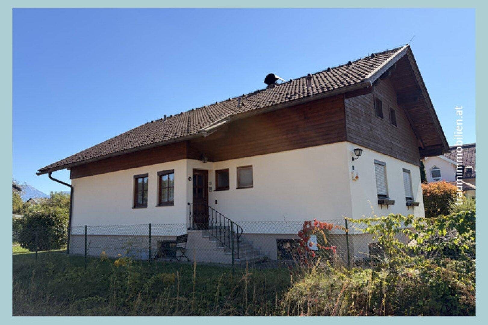 Seitenansicht des Hauses mit Eingangsbereich, Garten und traditionellem Satteldach.