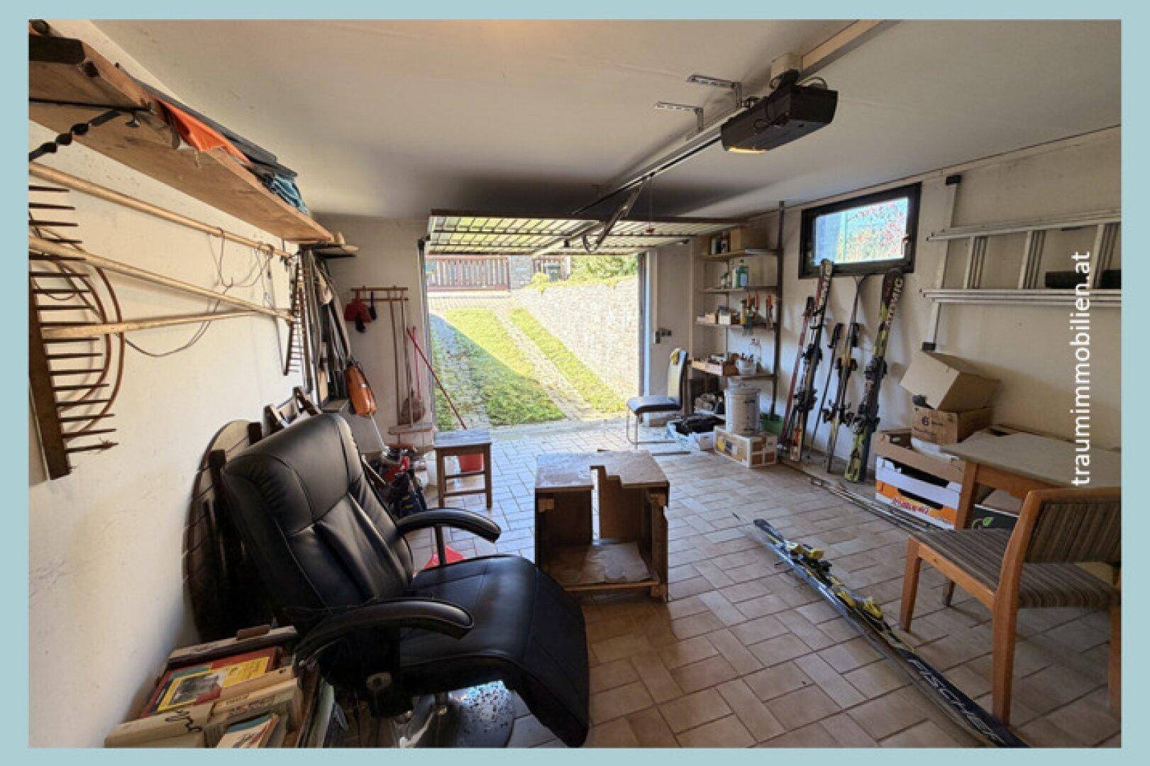 Geräumige Garage mit Fliesenboden, Stauraum und Skiausrüstung.