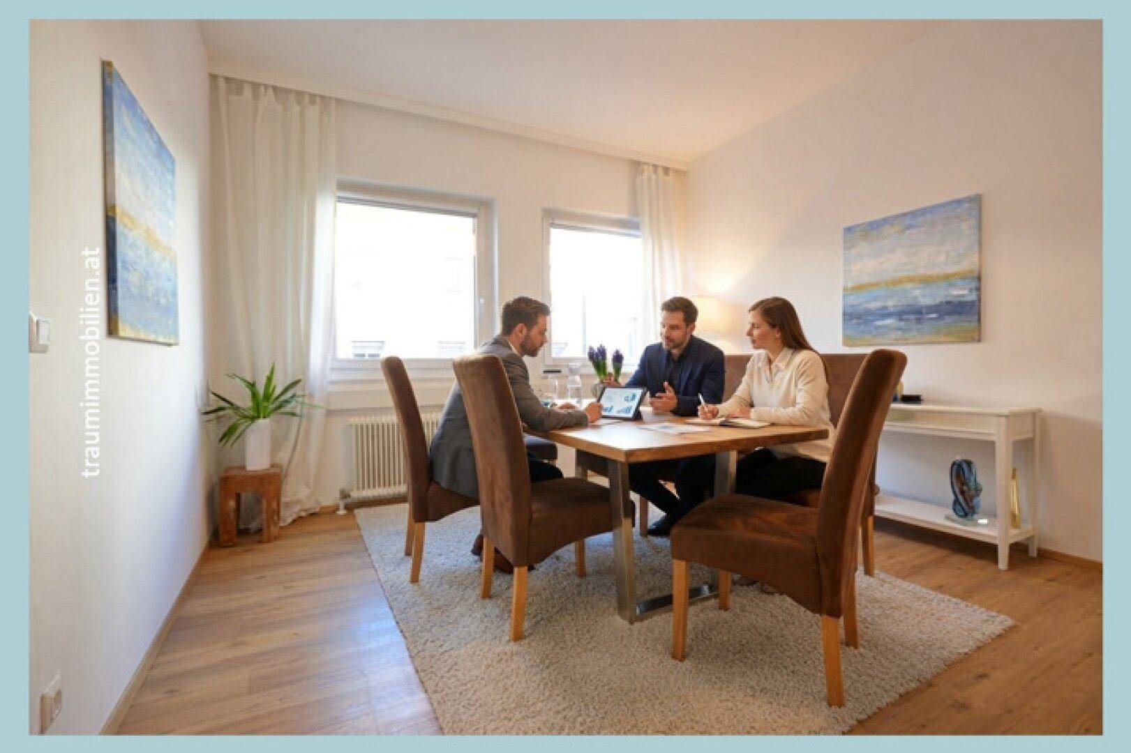 Besprechungsraum mit Holztisch, bequemen Stühlen und zwei Fenstern für natürliches Licht.