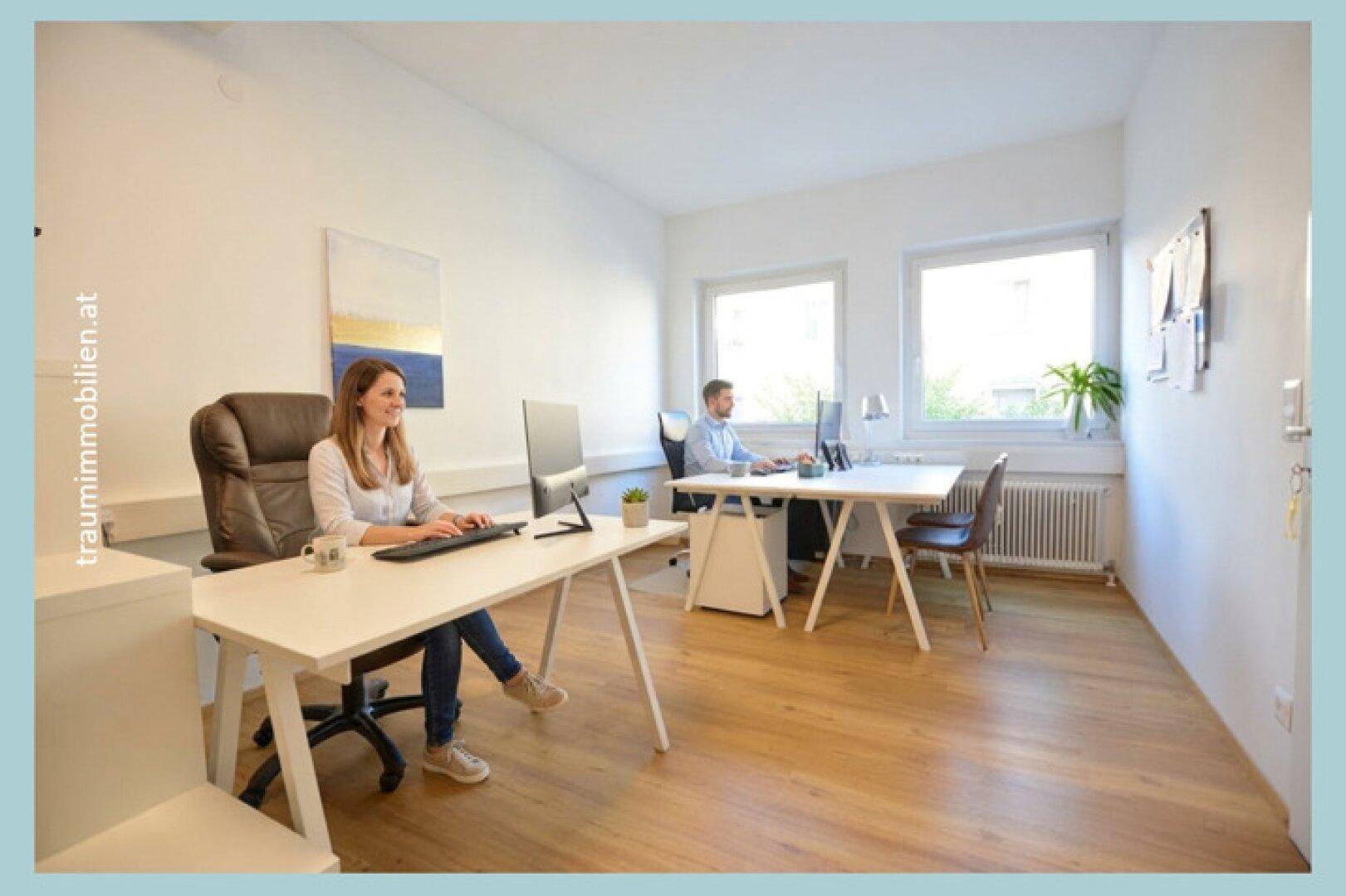Helles Büro mit zwei Arbeitsplätzen, großen Fenstern und einem warmen Holzfußboden.