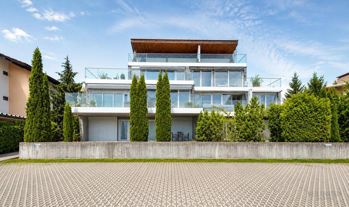 Moderne Wohnanlage mit mehreren Etagen, großen Glasfronten und Balkonen, umgeben von Grün.