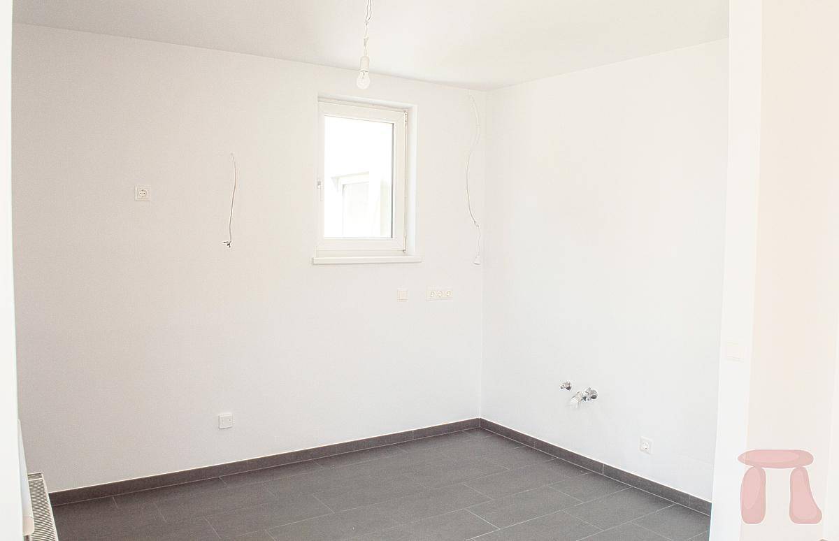 Leerer Raum mit dunklen Fliesen und sichtbaren Anschlüssen, ideal für eine Küche oder einen Hauswirtschaftsraum.