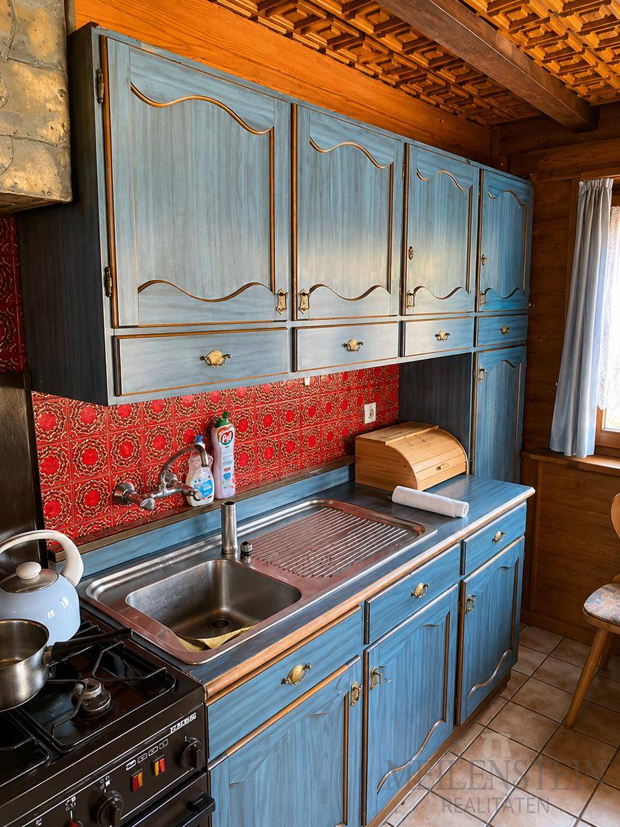 Traditionelle Küche mit blauen Holzschränken, Spüle und Gasherd.