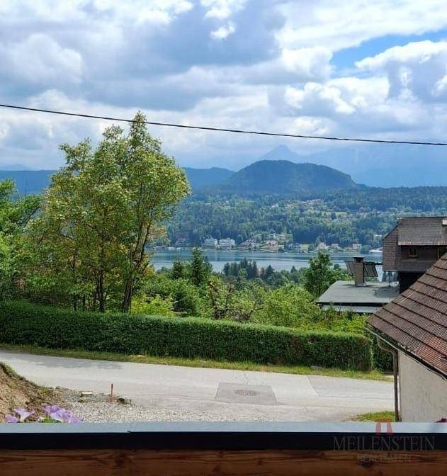 Panoramablick auf einen See und die umliegende Landschaft unter einem bewölkten Himmel.