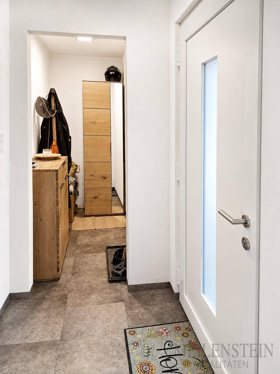 Einladender Eingangsbereich mit Holzmöbeln, Garderobe und Fliesenboden, hell und funktional.