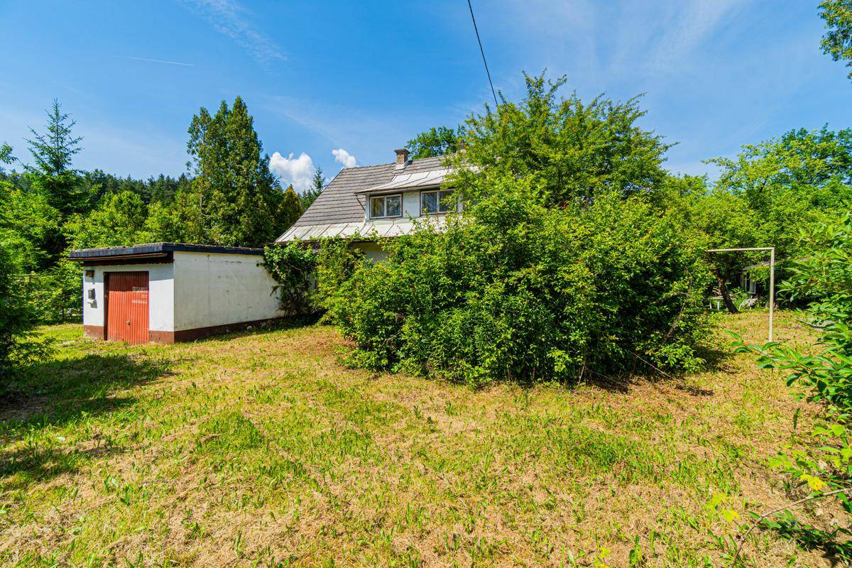 Freistehendes Haus mit Nebengebäude, umgeben von üppiger Vegetation und Rasenfläche.