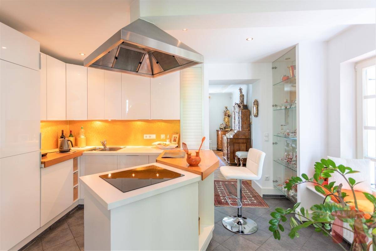 Moderne Küche mit weißen Hochglanzfronten, Kochinsel und Frühstücksbar.