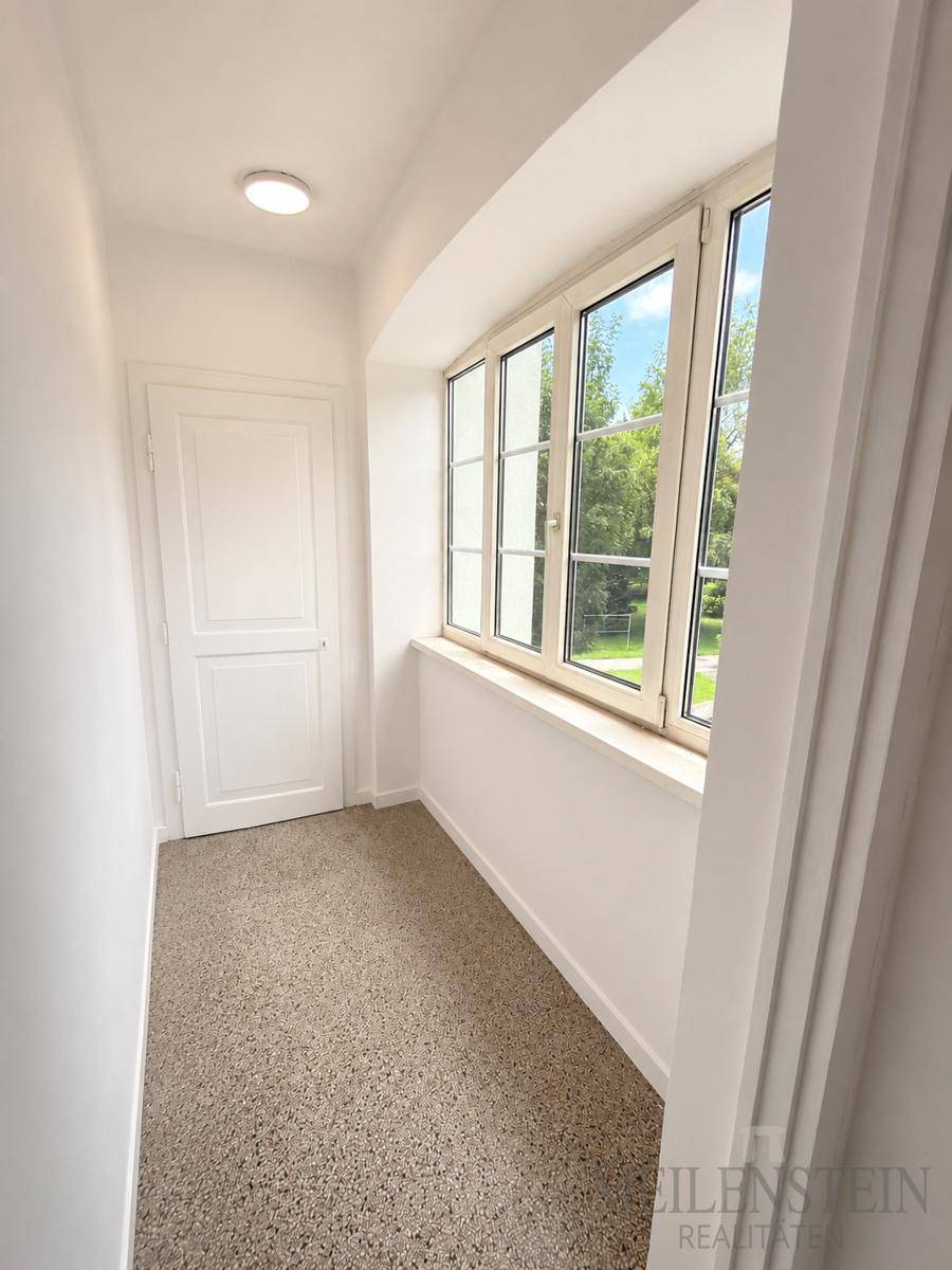 Schmaler Eingangsbereich oder Flur mit Fenster und Fliesenboden, der viel Tageslicht hereinlässt.