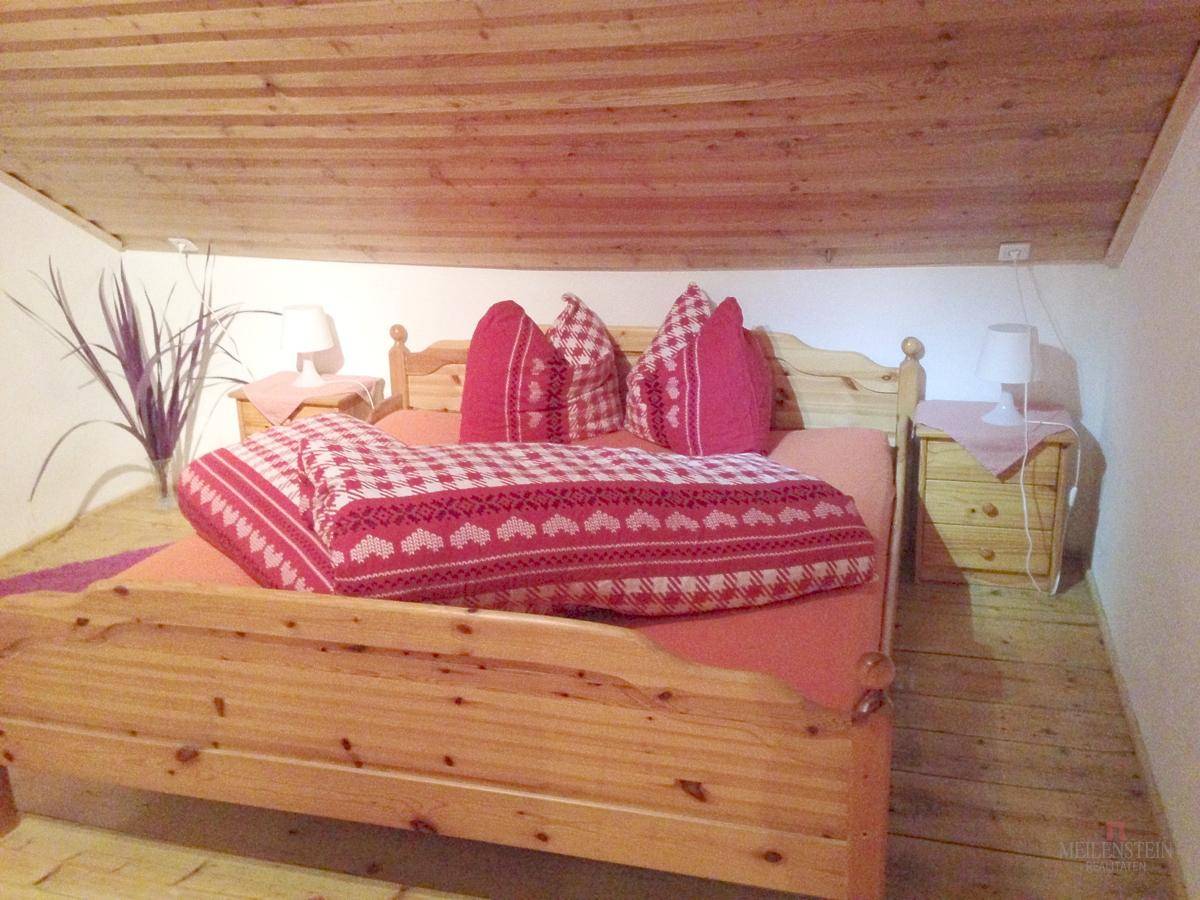 Rustikales Schlafzimmer mit Holzboden, Holzdecke und traditioneller Bettwäsche.