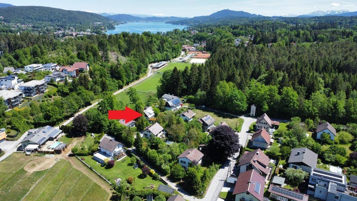 Luftaufnahme einer Wohnsiedlung mit See- und Bergblick, das Objekt ist mit einem Pfeil markiert.