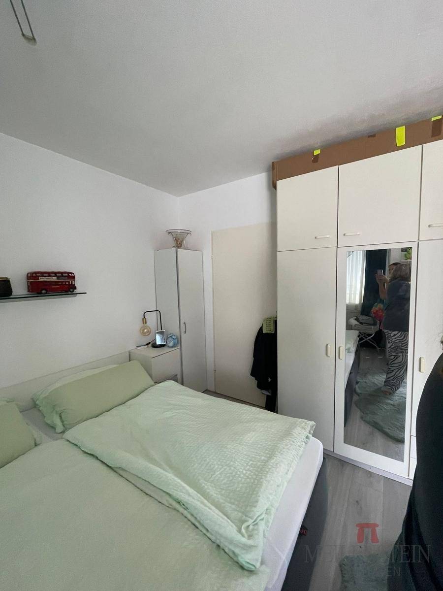 Schlafzimmer mit Doppelbett, weißem Kleiderschrank und Spiegeln.