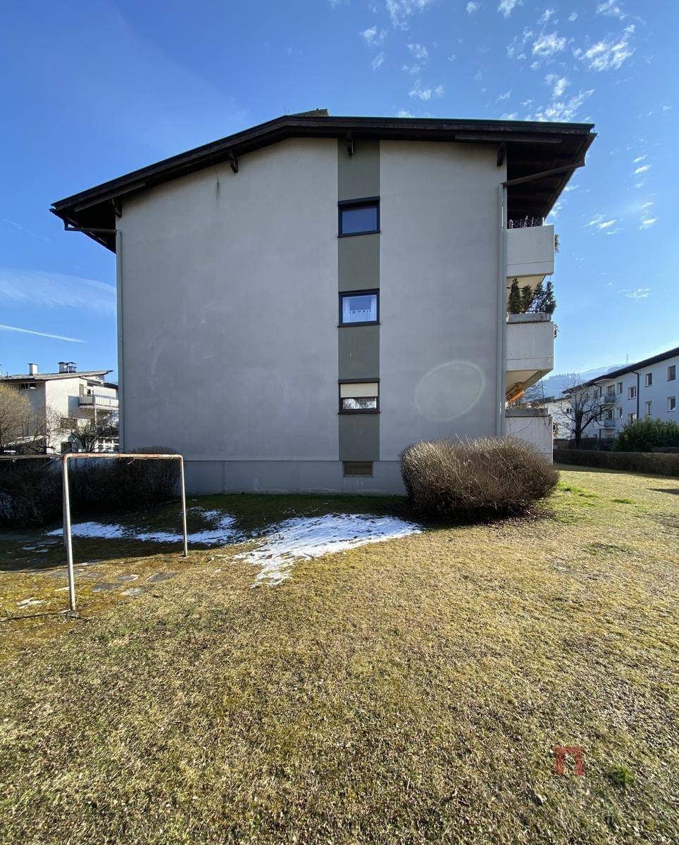 Gebäudeseite mit Rasenfläche und einem kleinen Fußballtor, umgeben von Natur.