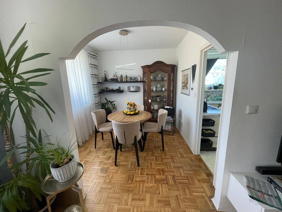 Essbereich mit Holzboden, rundem Tisch und Vitrine, offen zum Wohnzimmer.