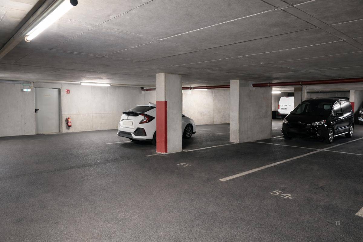 Tiefgarage mit markierten Stellplätzen und Säulen, die den Raum strukturieren, und geparkten Fahrzeugen.