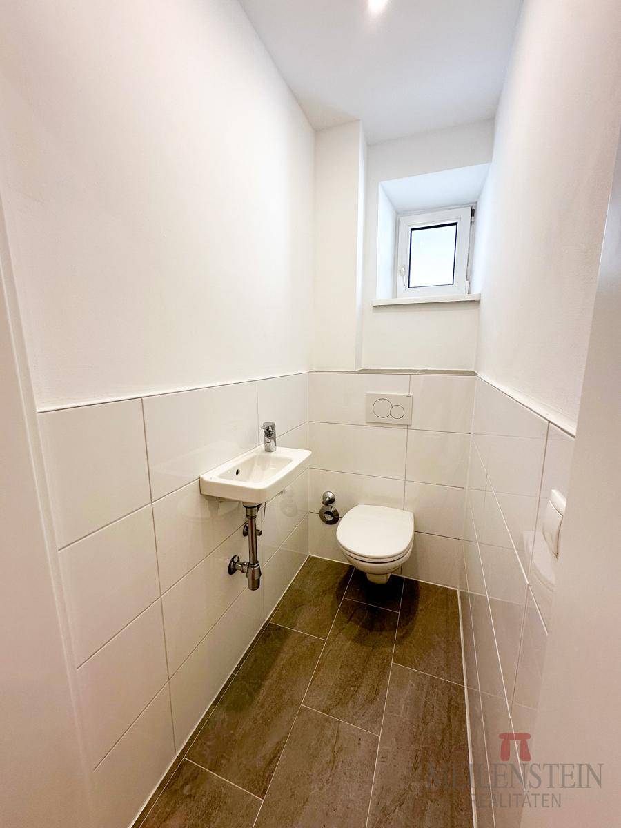 Kleines Gäste-WC mit Waschbecken, Toilette und Fenster, in modernem Design gehalten.