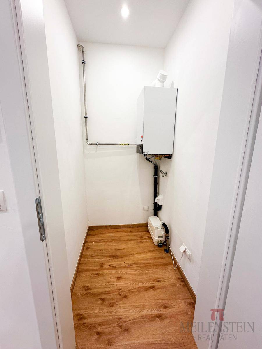 Kleiner Hauswirtschaftsraum mit Heizungsanlage und Holzboden, ideal für Technik und Lagerung.