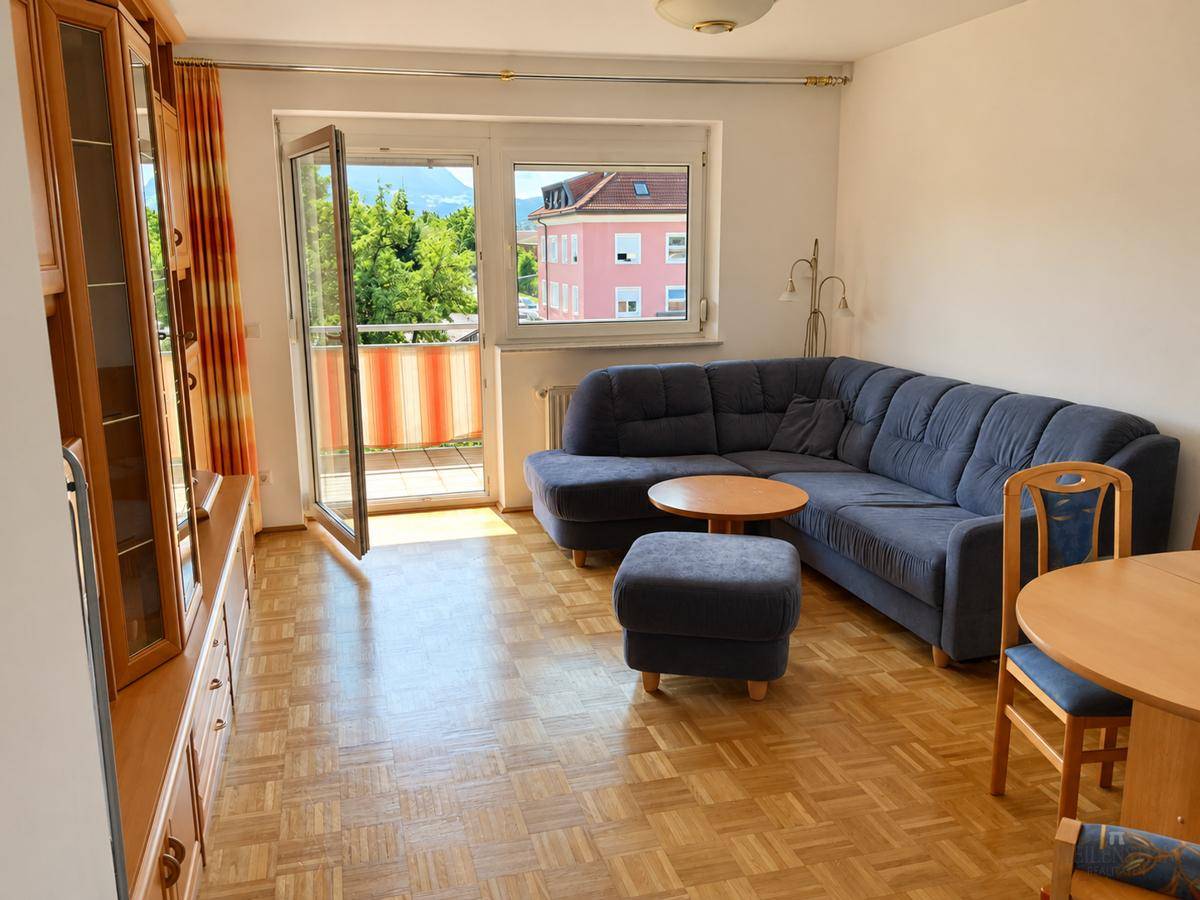 Geräumiges Wohnzimmer mit traditioneller Einrichtung, Parkettboden und Zugang zum Balkon.