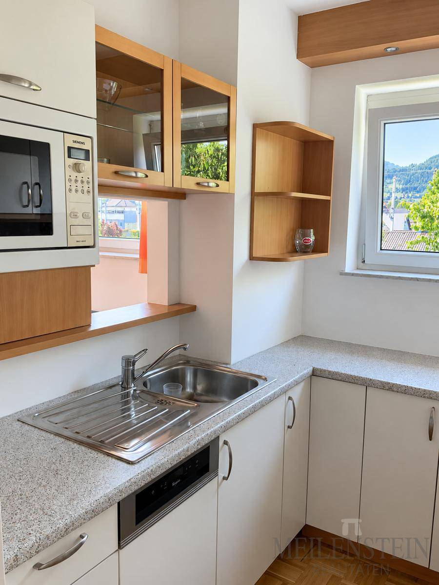 Funktionale Küche mit weißen Schränken, Granit-Arbeitsplatte und integrierter Mikrowelle.
