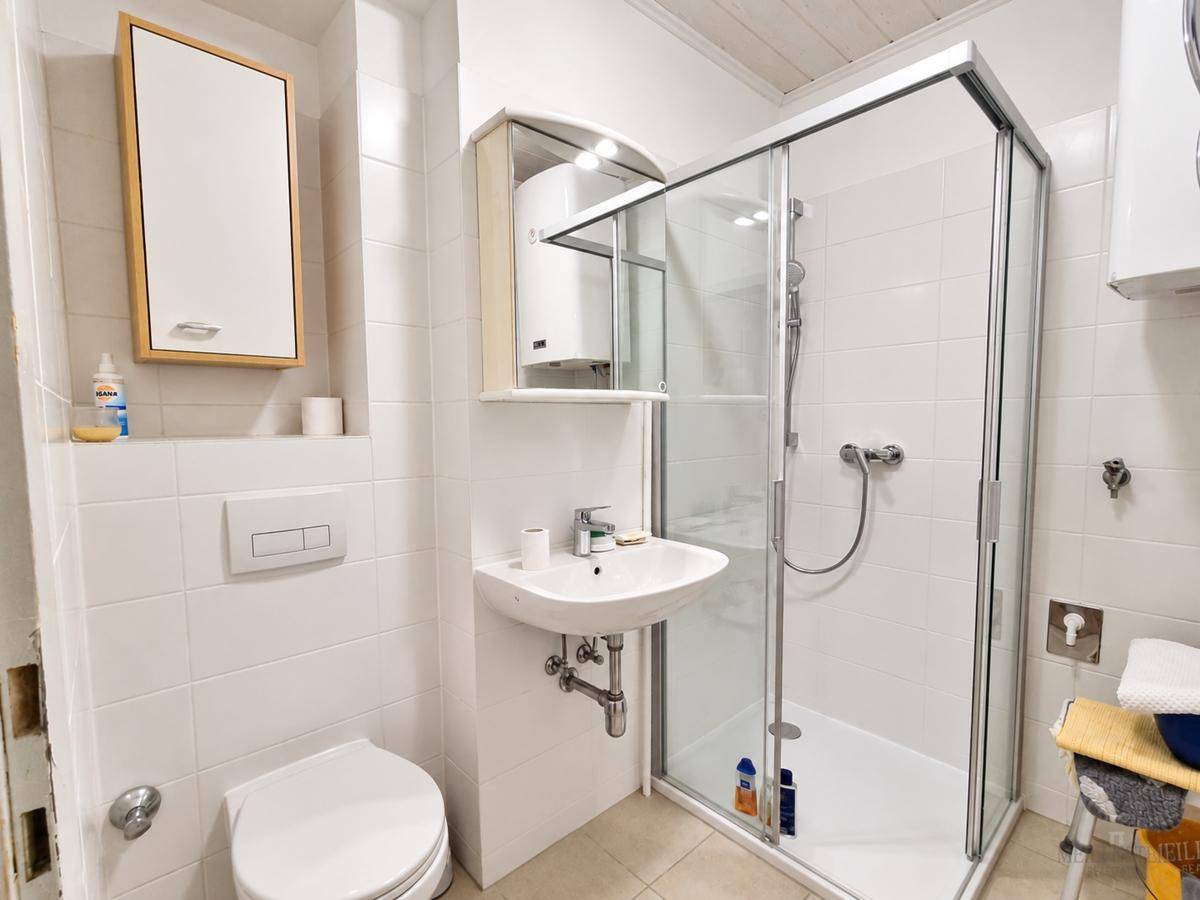 Modernes Badezimmer mit Dusche, WC, Waschbecken und weißen Fliesen.