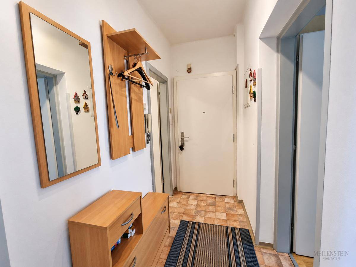 Heller Flur mit Spiegel, Garderobe und praktischem Schuhschrank.