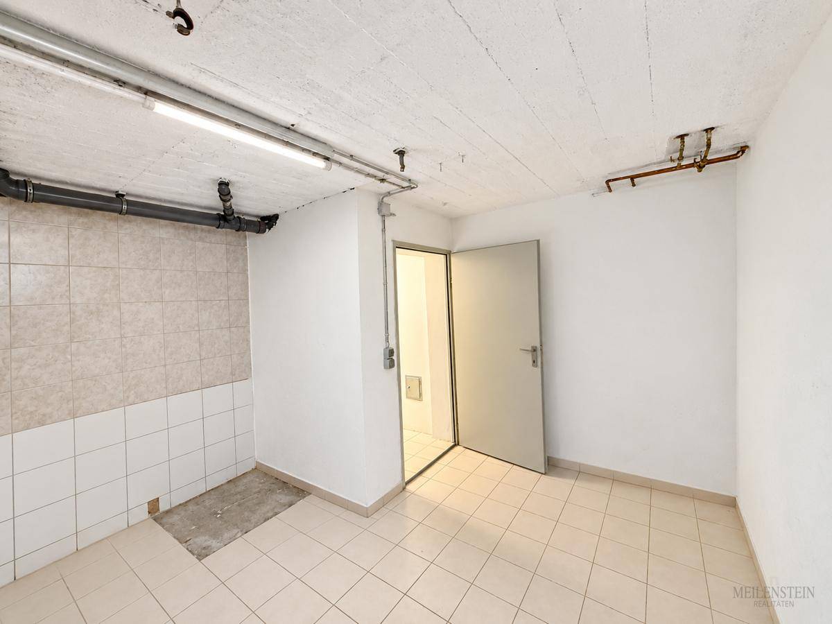 Heller, leerer Kellerraum mit Fliesenboden und teilweise gefliesten Wänden, bereit zur Nutzung.