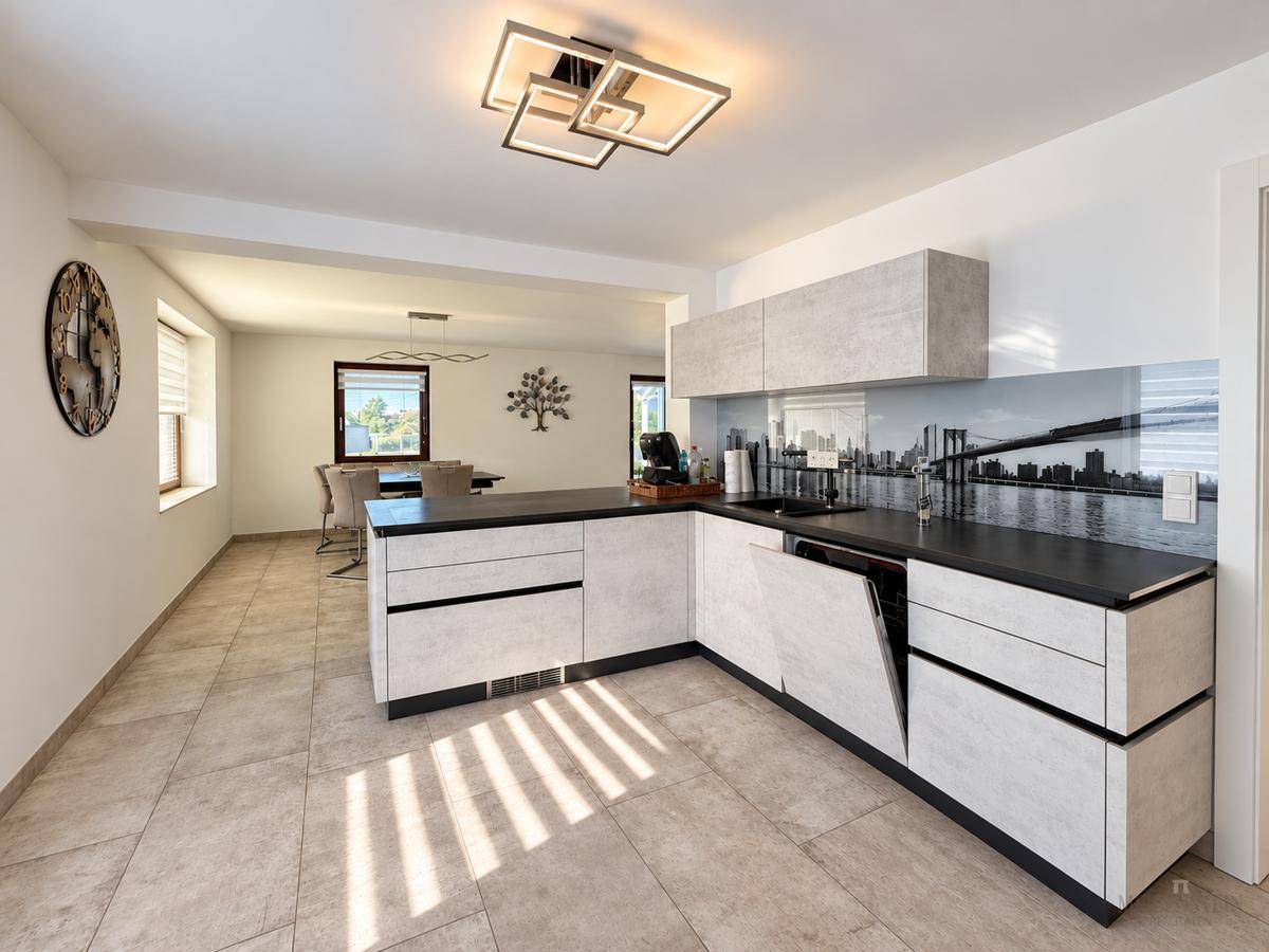 Moderne Küche mit grauen Schränken, dunkler Arbeitsplatte und stilvoller Rückwand.