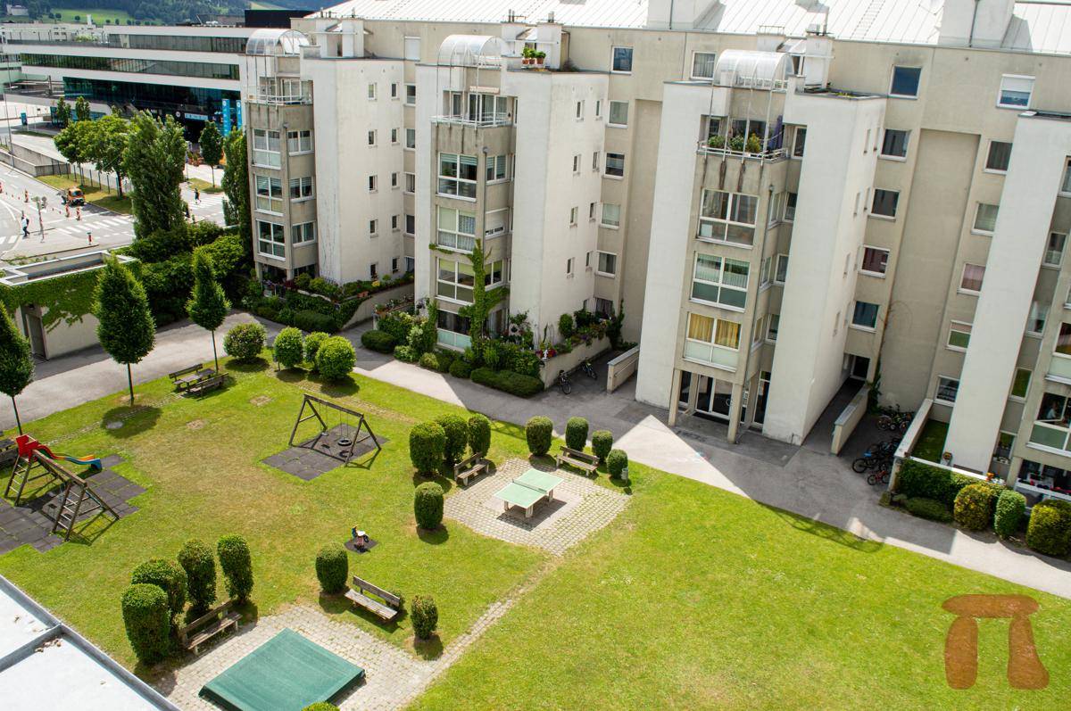 Luftaufnahme des Wohnkomplexes mit Spielplatz, Grünflächen und umliegender Infrastruktur.