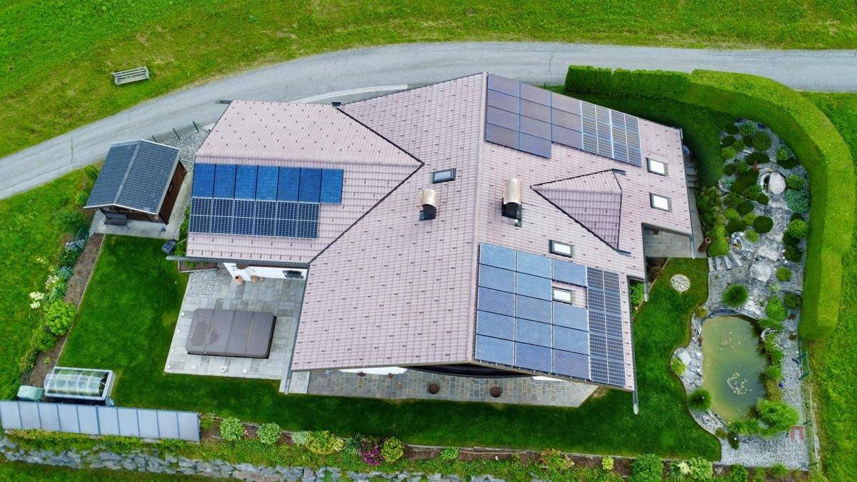 Draufsicht auf das Haus mit umfangreichen Solarmodulen auf dem Ziegeldach und einem Whirlpool im Garten.