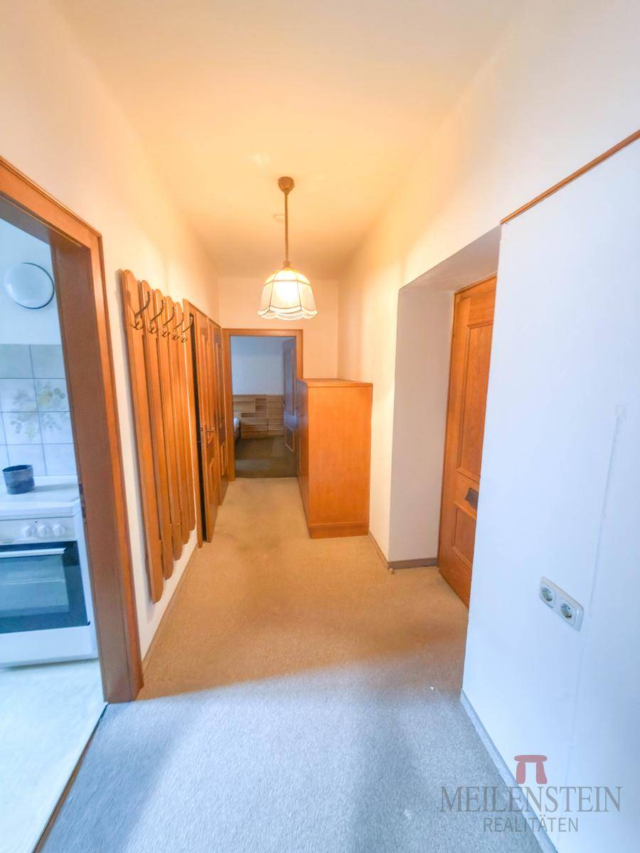 Heller Flur mit Teppichboden, Holztüren und Garderobe.
