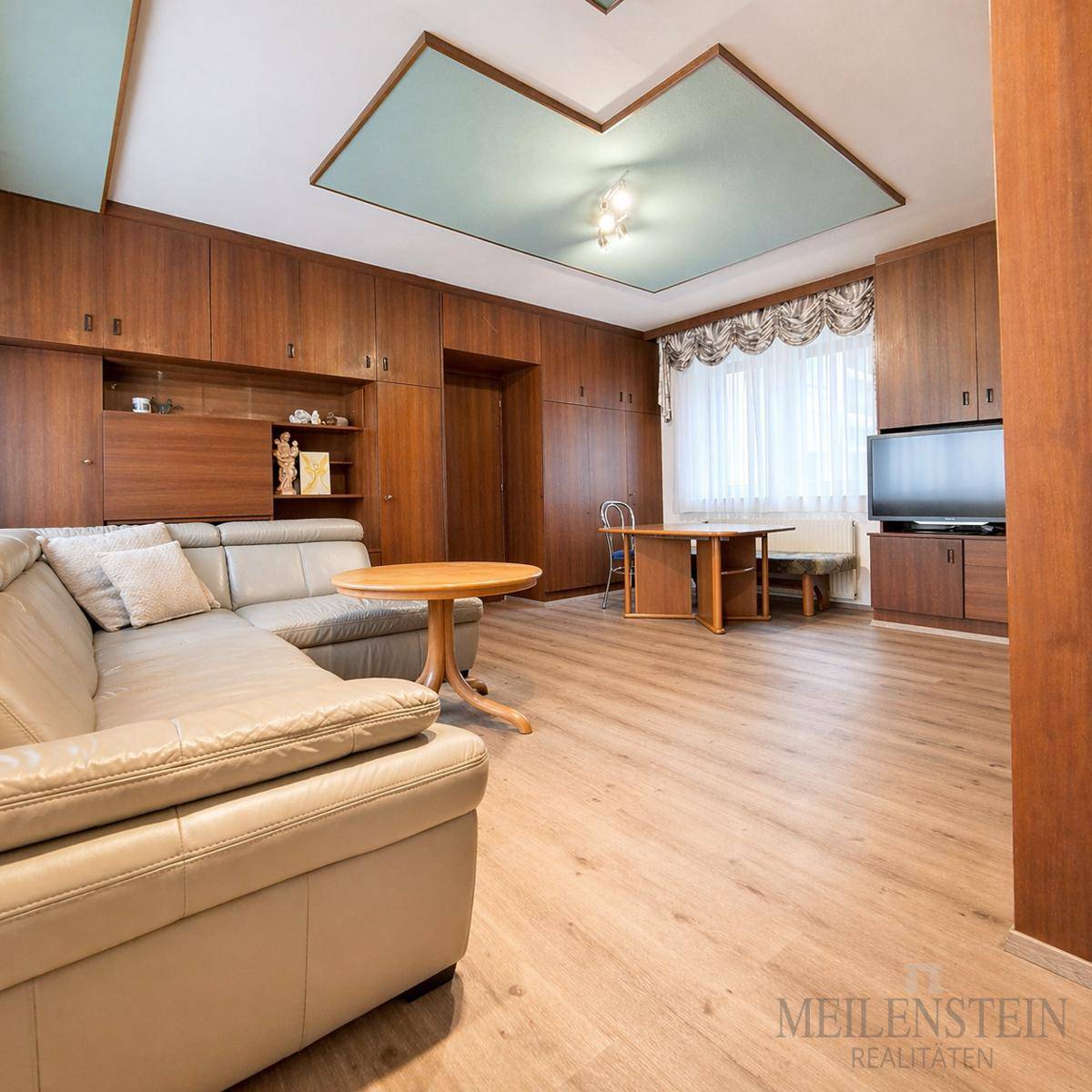 Geräumiges Wohnzimmer mit Laminatboden, Holzmöbeln und einer dekorativen Decke, die viel Platz bietet.