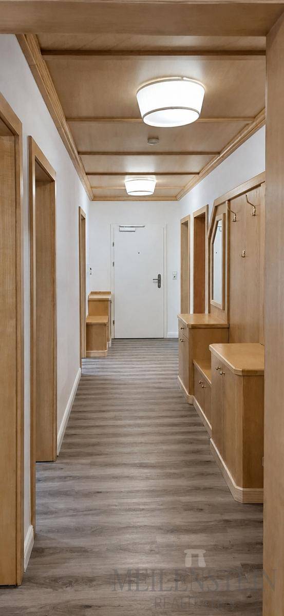 Heller Flur mit Holzdeckenverkleidung, Einbaumöbeln und Garderobe, die eine einladende Atmosphäre schafft.