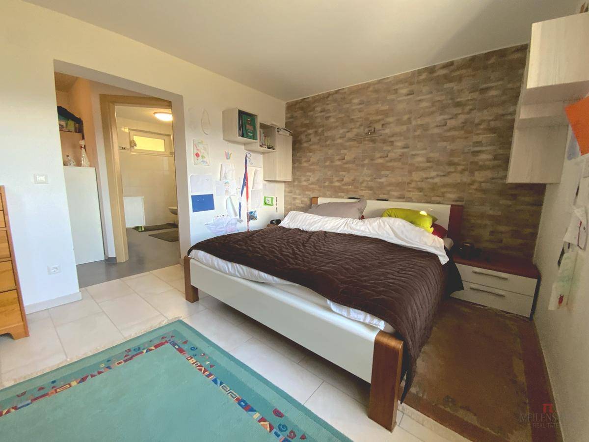 Schlafzimmer mit Doppelbett, Akzentwand und Zugang zu einem angrenzenden Badezimmer.