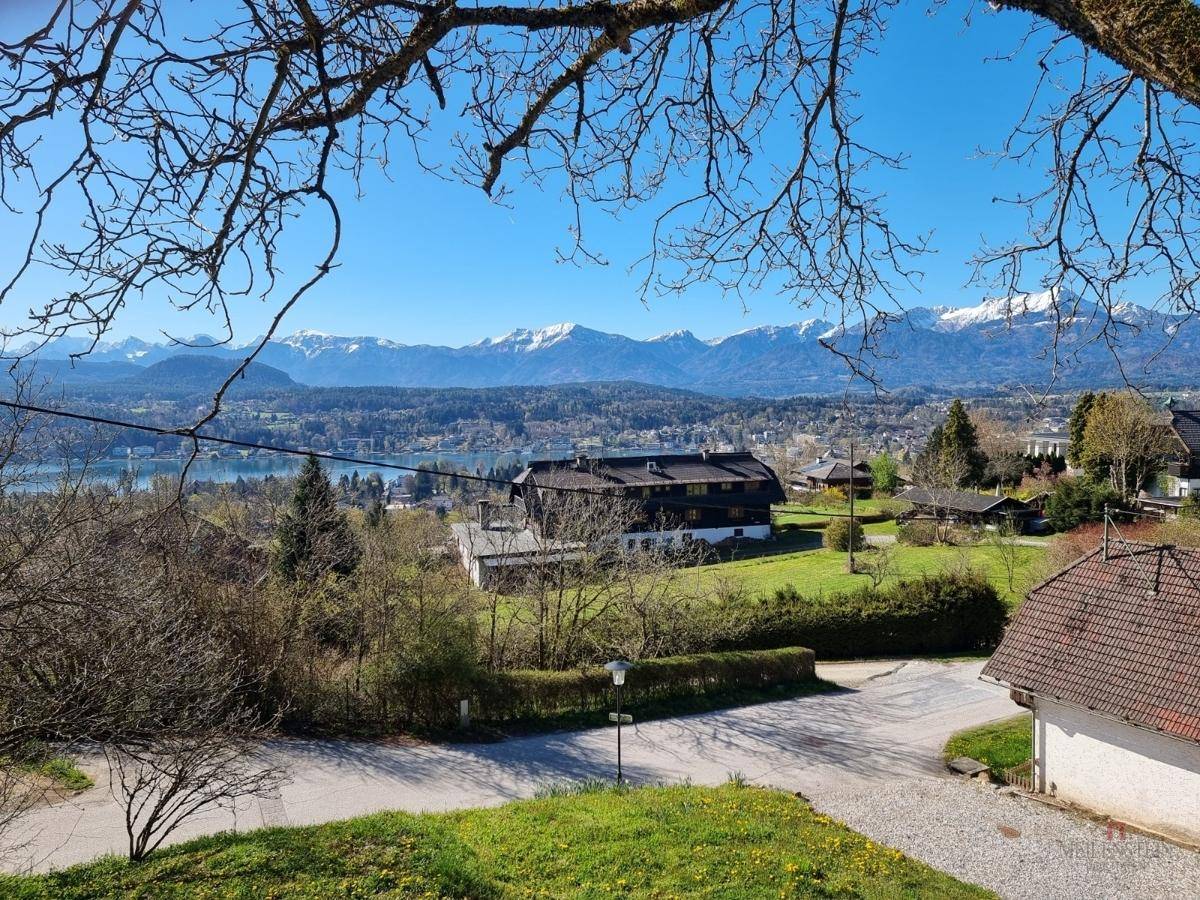 Weitläufiger Blick über eine Seenlandschaft und bewaldete Hügel bis zu schneebedeckten Bergen.