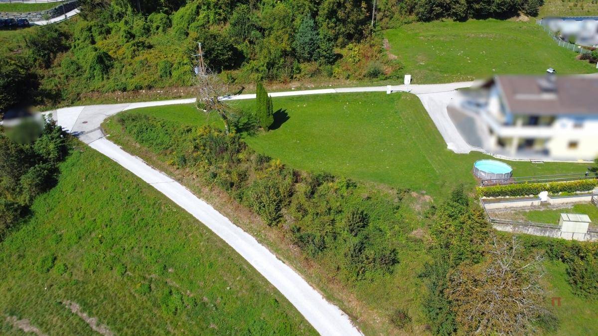 Luftaufnahme eines Grundstücks mit grünen Flächen, Zufahrtswegen und einem Haus im Hintergrund.