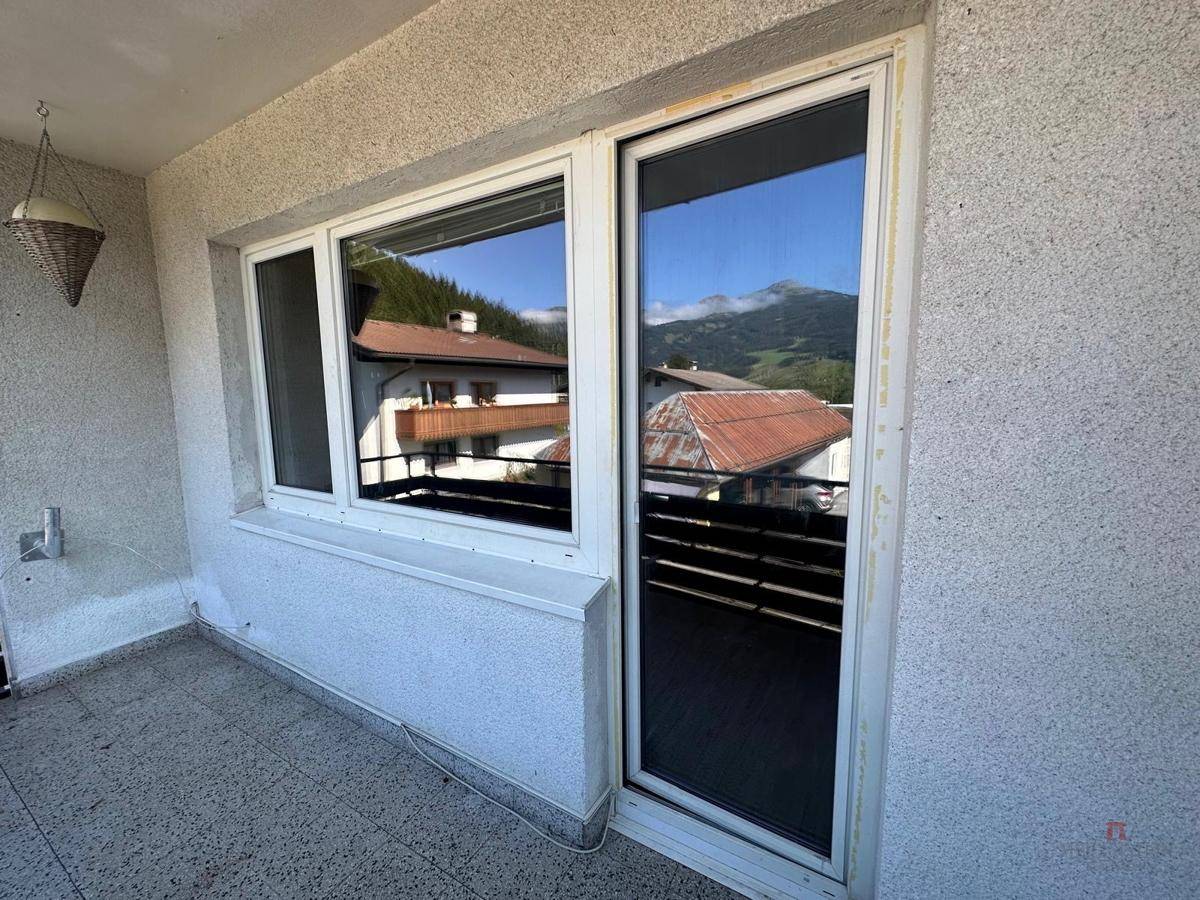 Balkontür und Fenster mit Blick auf die Umgebung, umgeben von einer strukturierten Fassade.