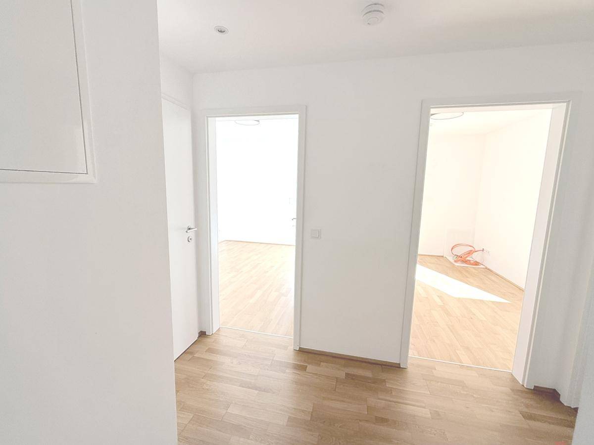 Heller Flur mit Parkettboden, der zu weiteren Zimmern der Wohnung führt.