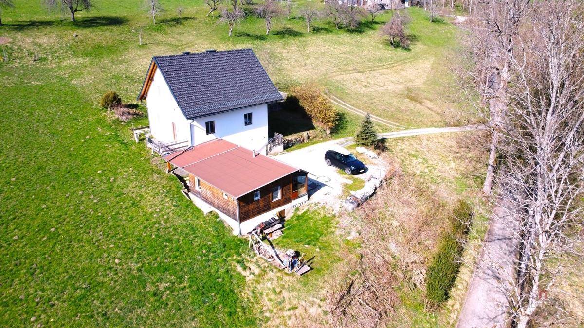 Luftaufnahme des Anwesens mit Haupthaus, Nebengebäude und Parkplatz in ländlicher Umgebung.