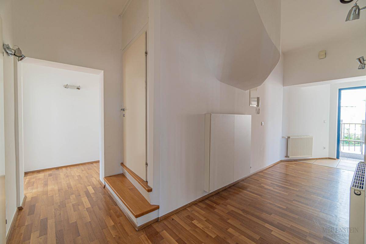 Geräumiger Wohnbereich mit Holzboden und Zugang zu einem Balkon, ideal für entspannte Stunden.