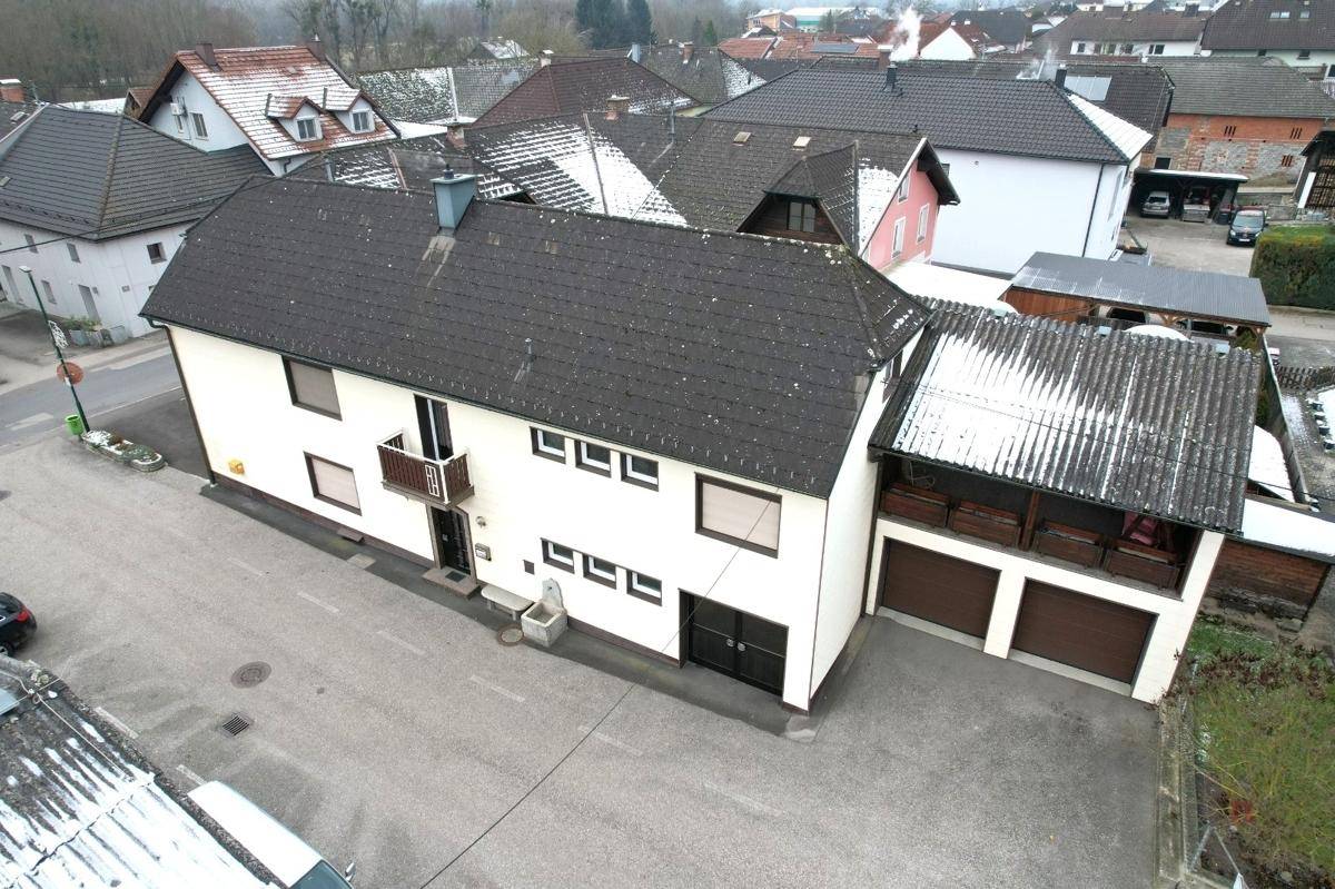 Luftaufnahme des Gebäudes mit angrenzender Garage, Parkplätzen und Satteldach.