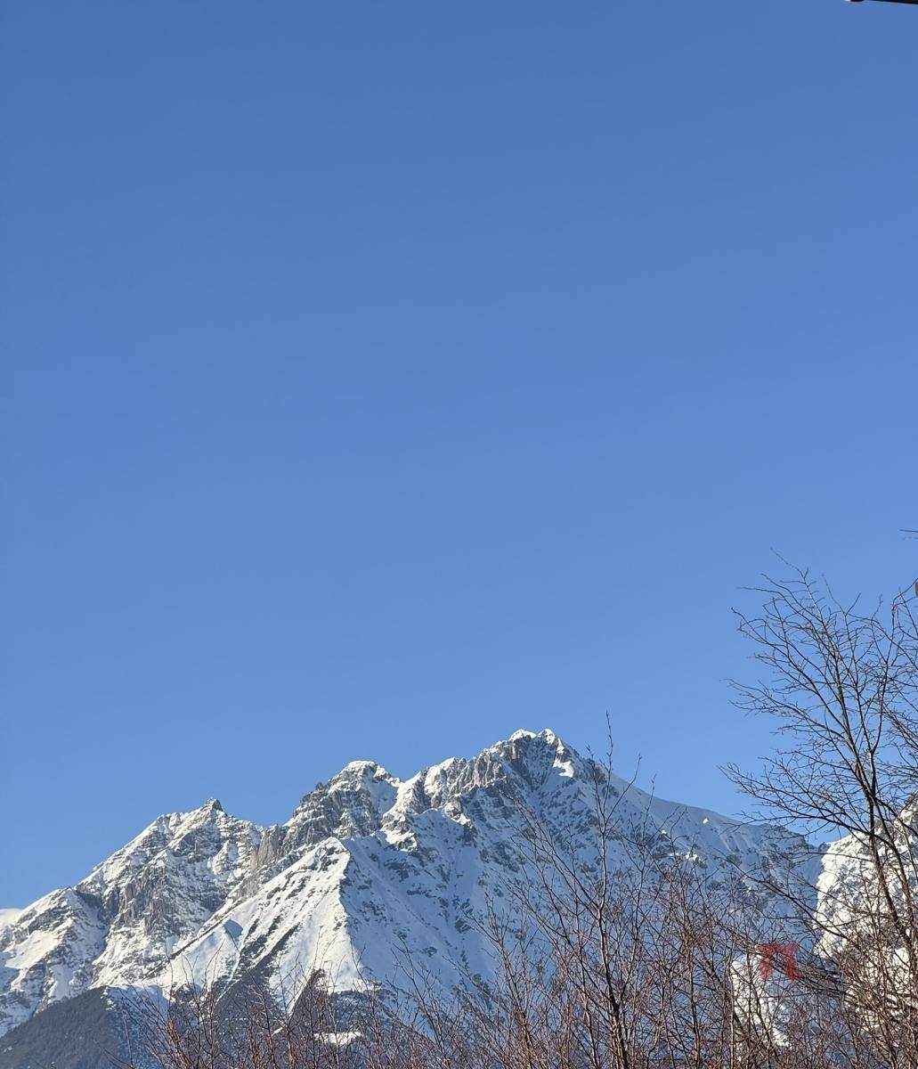 Majestätischer Blick auf schneebedeckte Berggipfel unter klarem blauem Himmel.