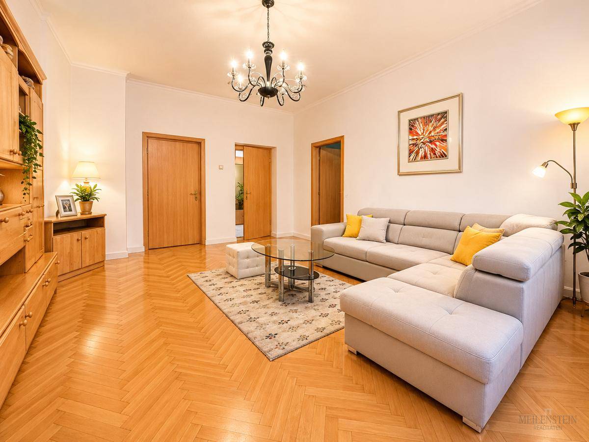 Helles Wohnzimmer mit Fischgrätparkett, gemütlicher Couch und mehreren Holztüren.