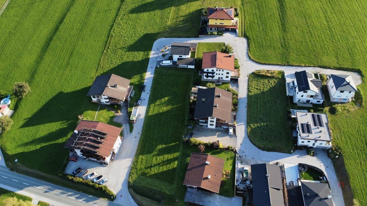 Luftaufnahme einer ländlichen Wohnsiedlung umgeben von weitläufigen grünen Feldern.