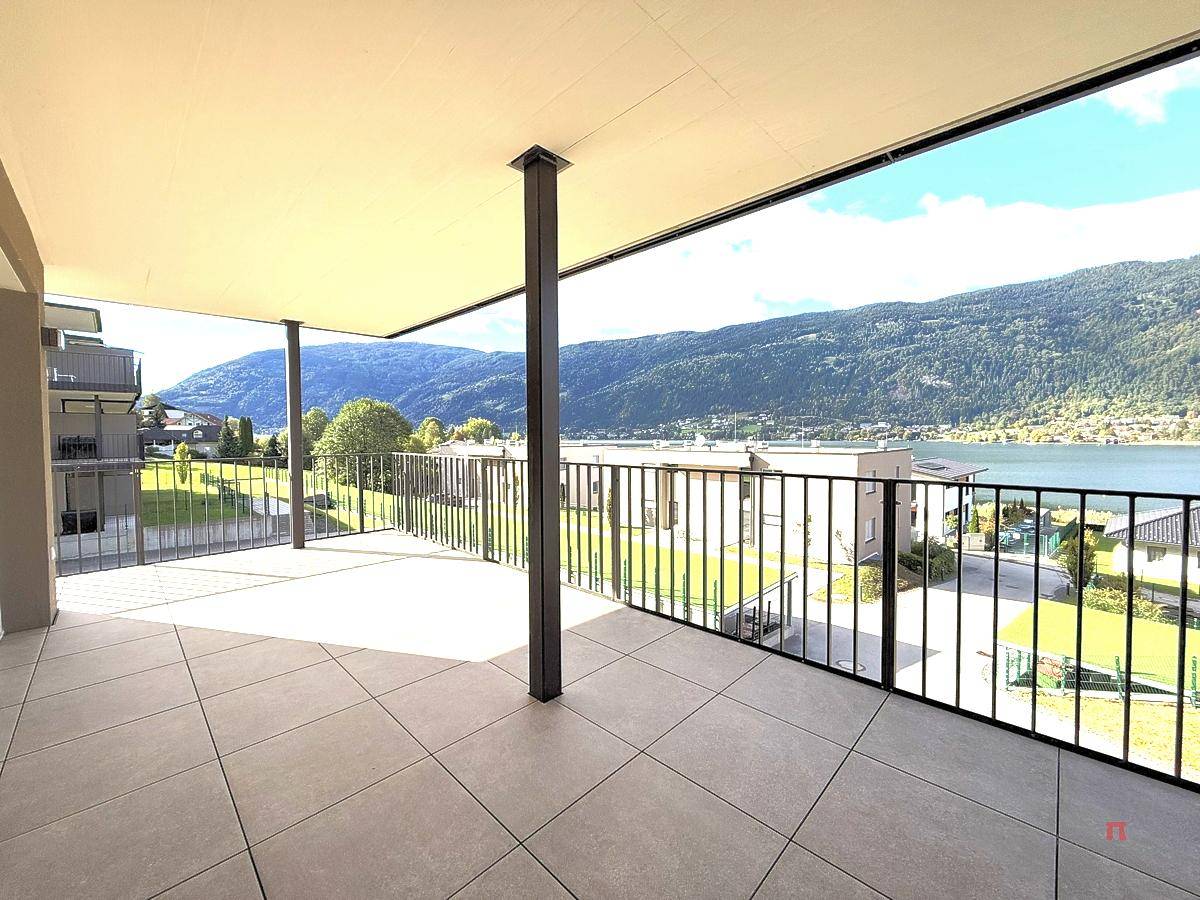 Geräumige Terrasse mit Fliesenboden und weitem Blick auf den See und die umliegenden Berge.