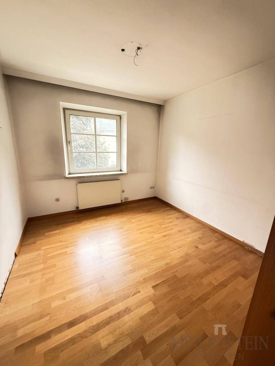 Helles Schlafzimmer mit Laminatboden und Fenster, das auf eine neue Gestaltung wartet.