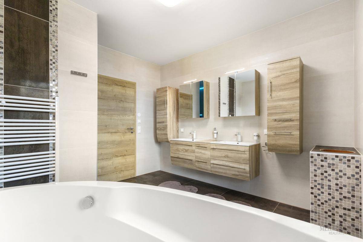 Modernes Badezimmer mit Badewanne, Doppelwaschbecken und beheiztem Handtuchhalter.