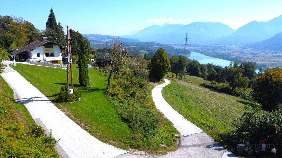 Panoramablick auf ein Haus mit weitläufigem Grundstück, umgeben von Bergen und einem Fluss.
