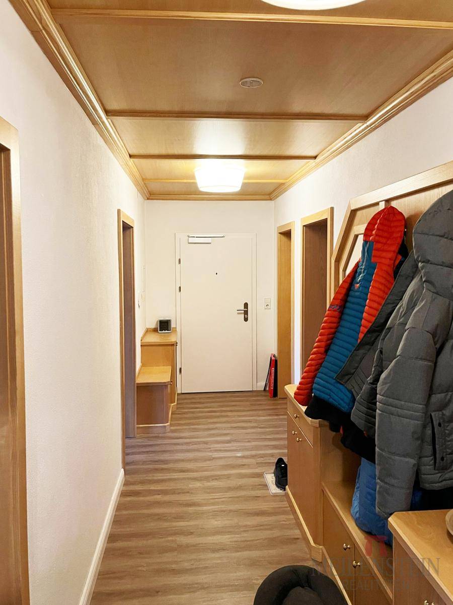 Eingangsbereich mit Garderobe, Spiegel und Blick auf die Eingangstür und den Flur.