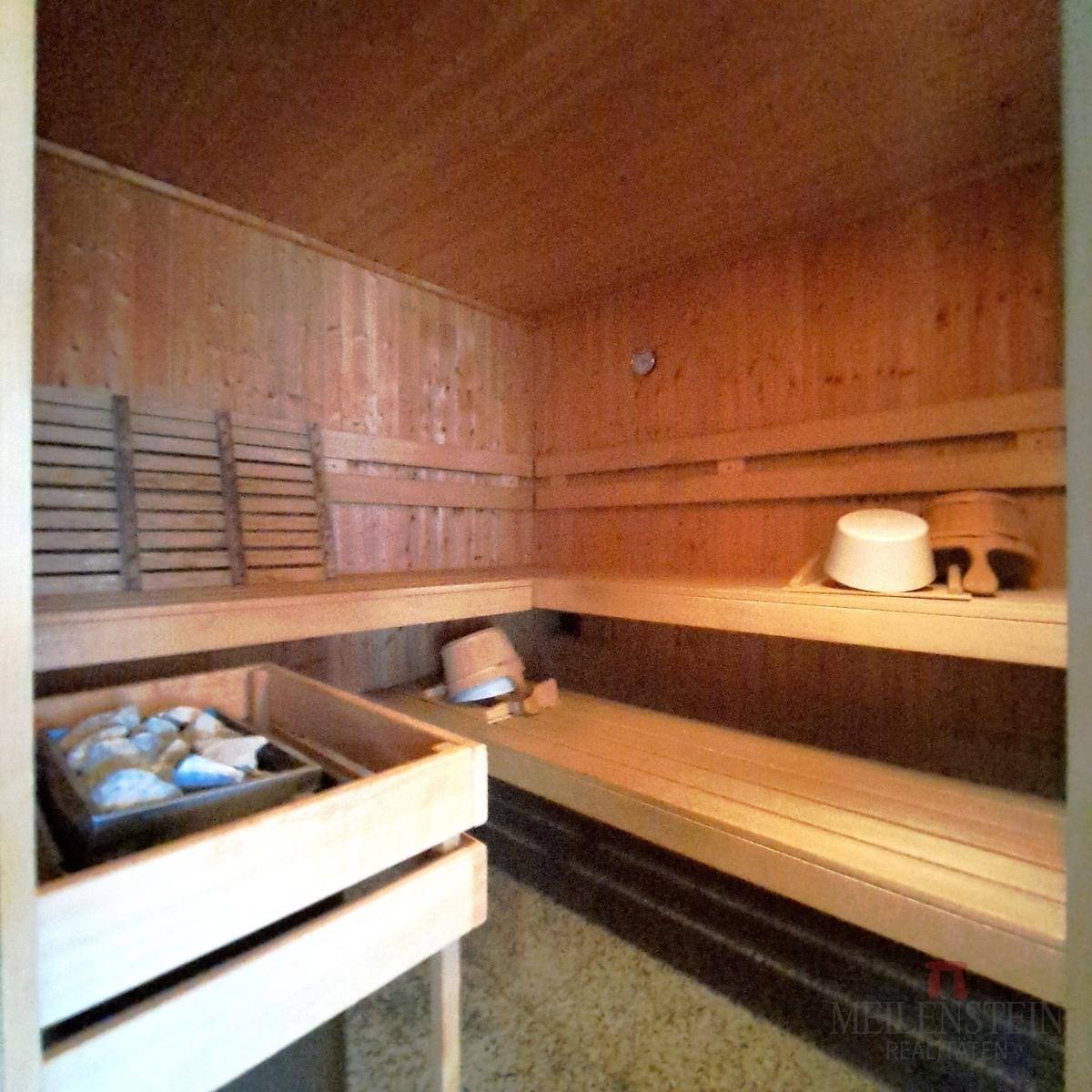 Innenansicht der Holzsauna mit Bänken, Saunaofen und traditionellem Design.
