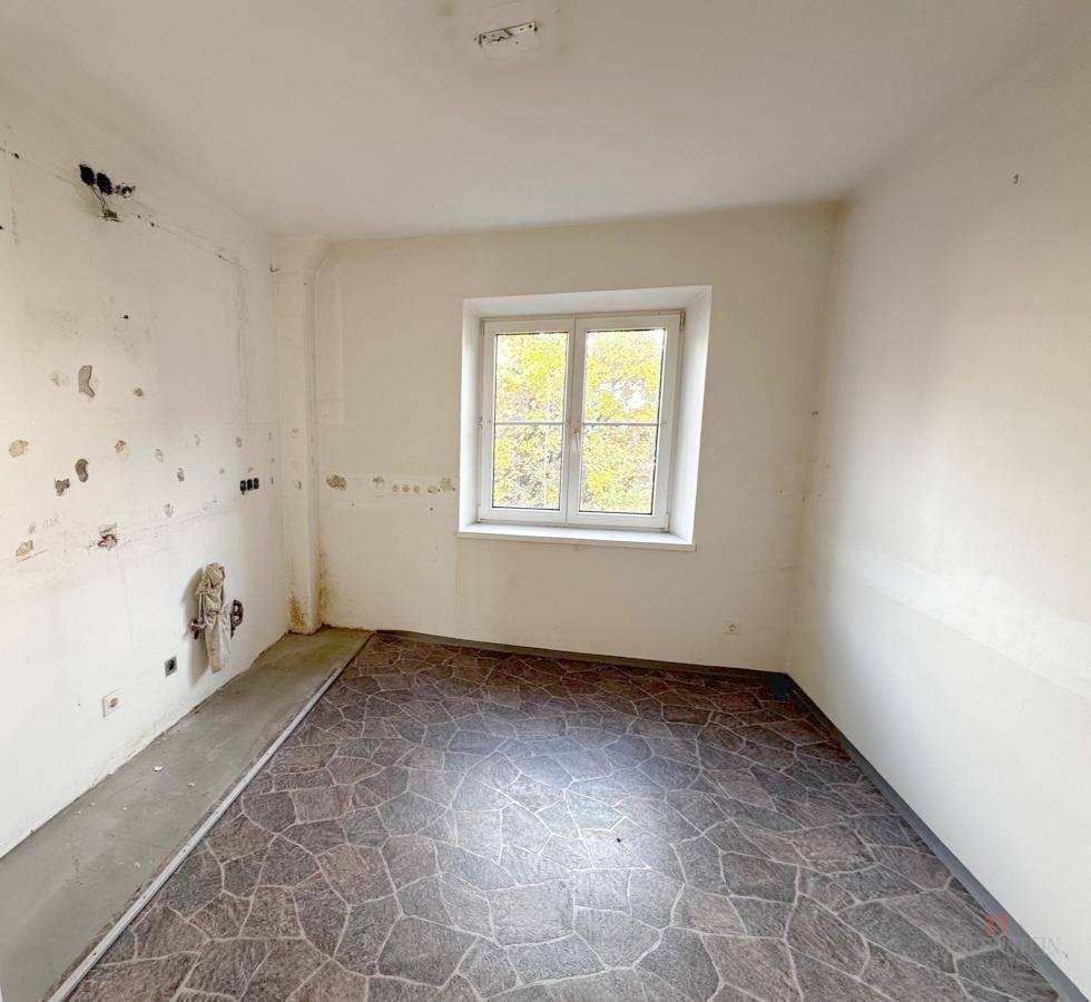 Raum mit gemustertem Boden und sichtbaren Gebrauchsspuren, der eine Renovierung benötigt.